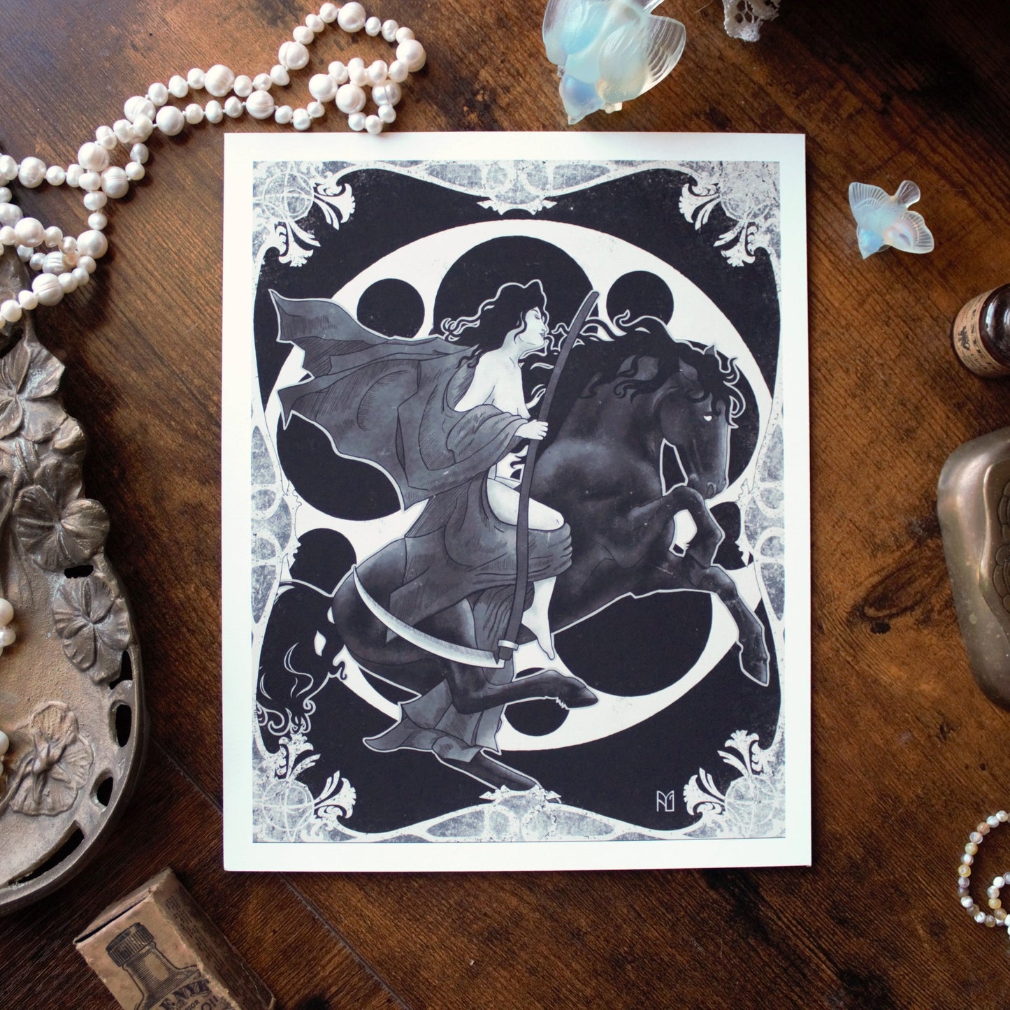 Decorative card with a woman and horse design on a wooden surface with decorative items.