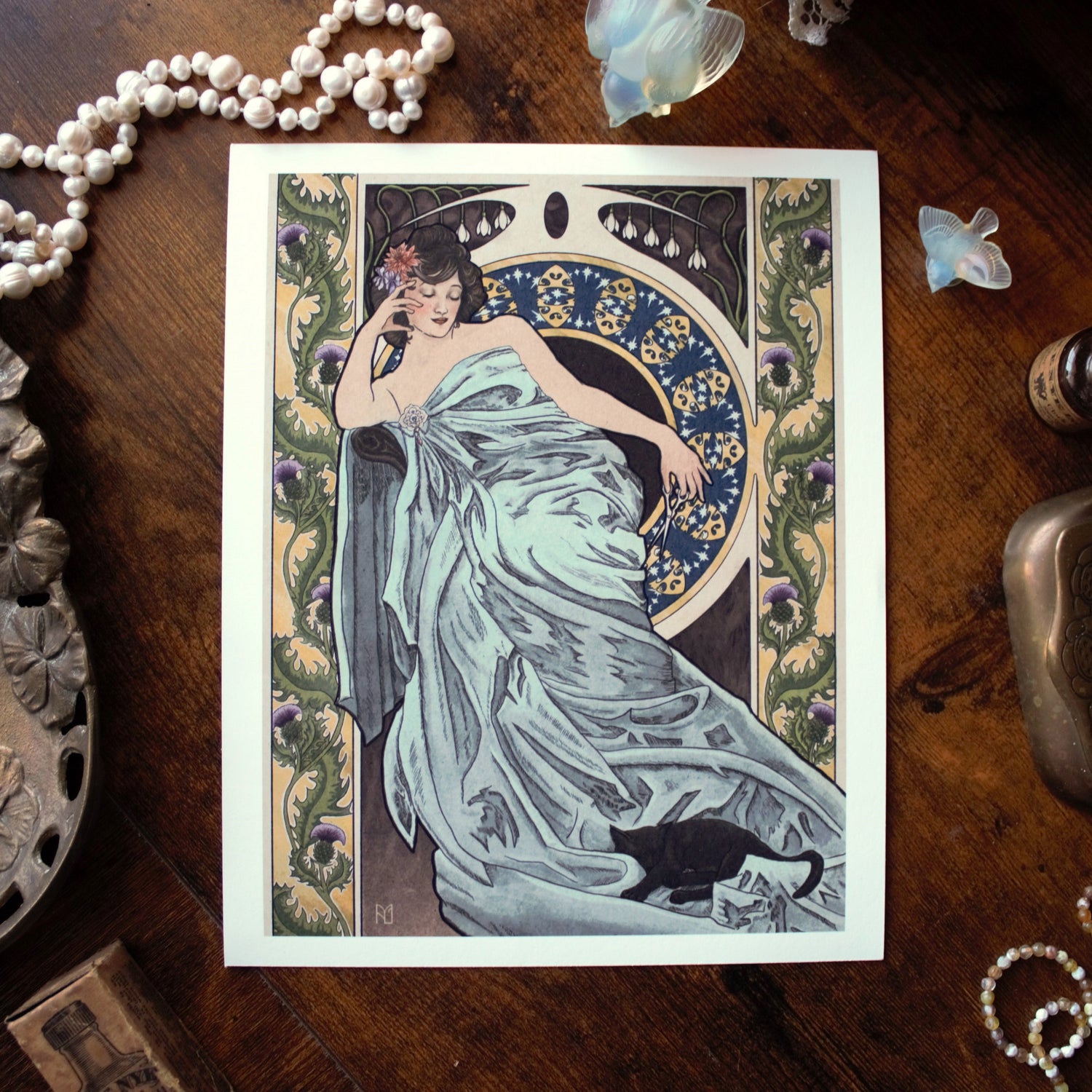 Art Nouveau-style illustration with a woman in a dress on a wooden surface with decorative items.
