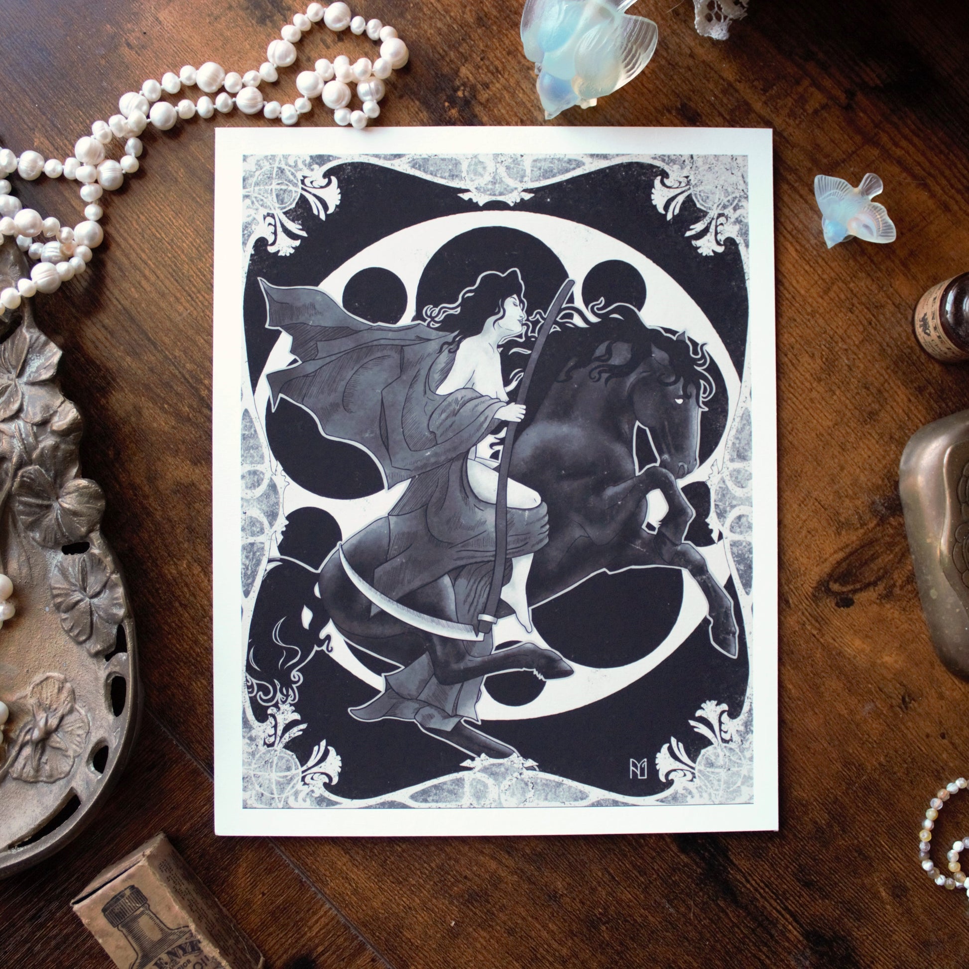 Decorative card with a woman and horse design on a wooden surface with decorative items.