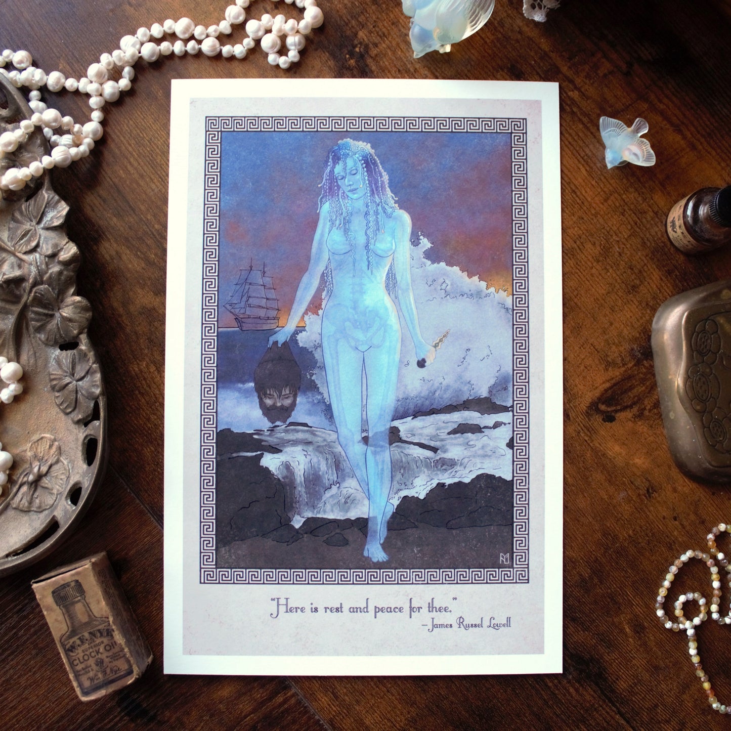 Art print of Medusa as a jellyfish holding Poseidon's head in front of a rock sea scape on a wooden surface with decorative items.