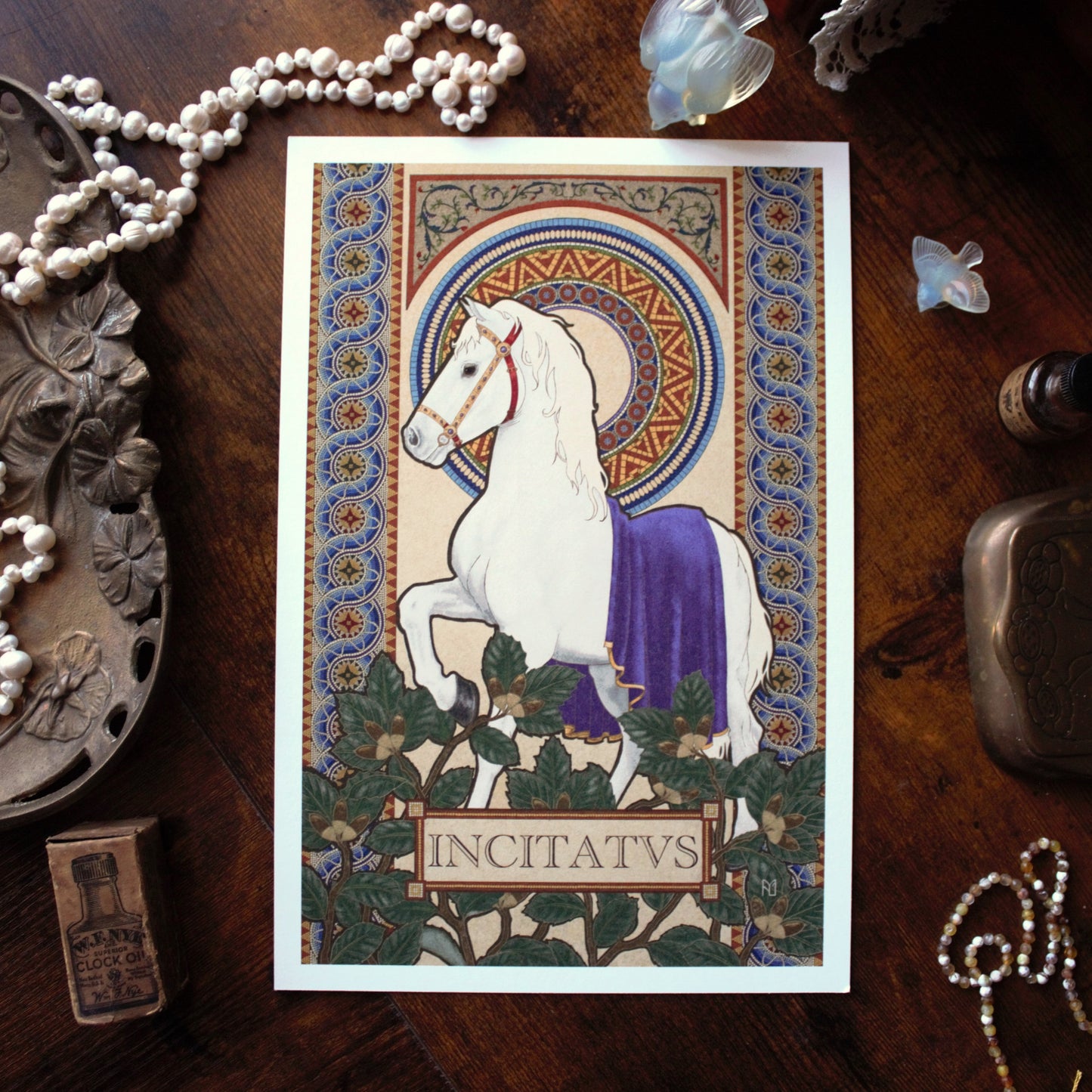 Decorative card with a white horse and purple blanket on a wooden surface with jewelry and a bottle.